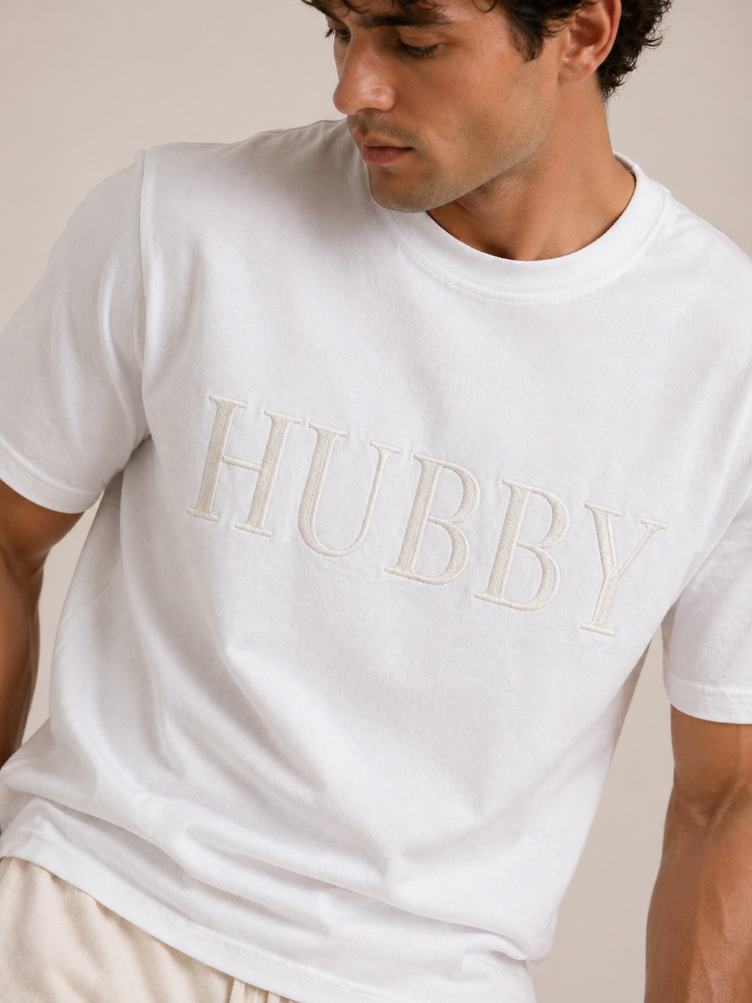 Man wearing a white t-shirt with 'HUBBY' printed on it against a neutral background