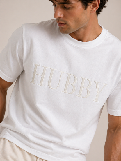 Man wearing a white t-shirt with 'HUBBY' printed on it against a neutral background