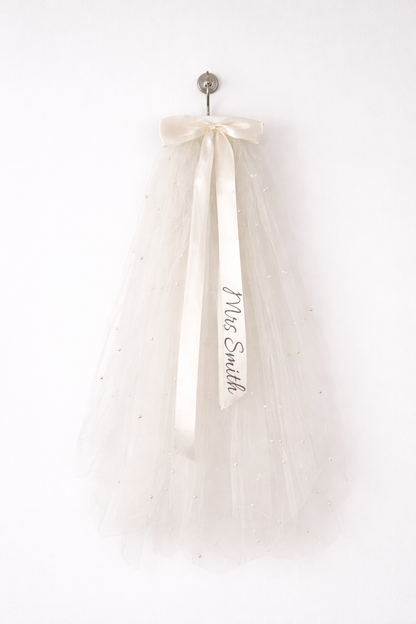 Say "I do" to a personalized veil for your hen do! 🎊 Keep it classy and sophisticated with your own message on the ribbon. With a secure comb grip, you’ll be ready to party all night! 